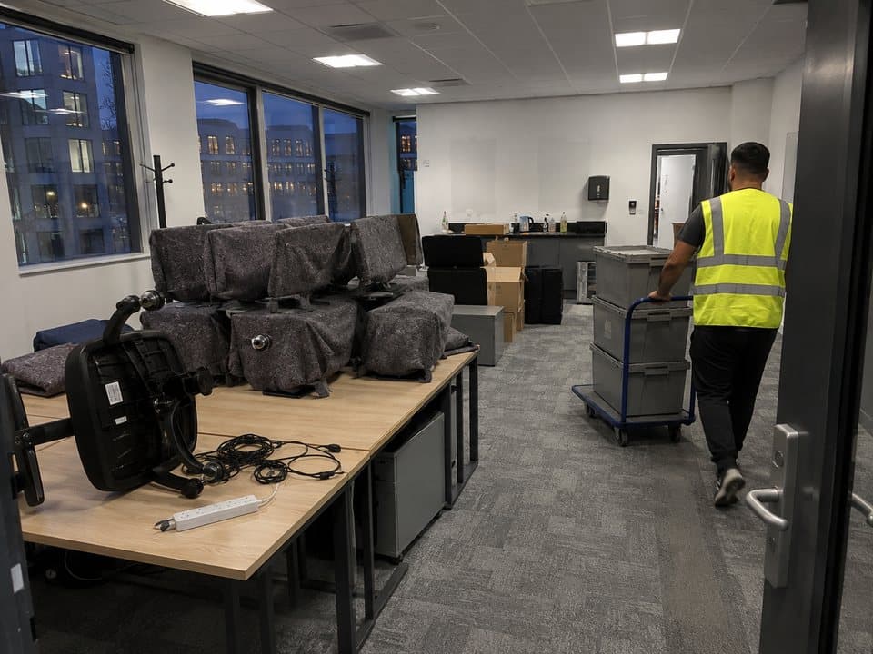 Office removals in London: part-emptied London office at dusk, with wrapped monitors stacked and crates on a trolley